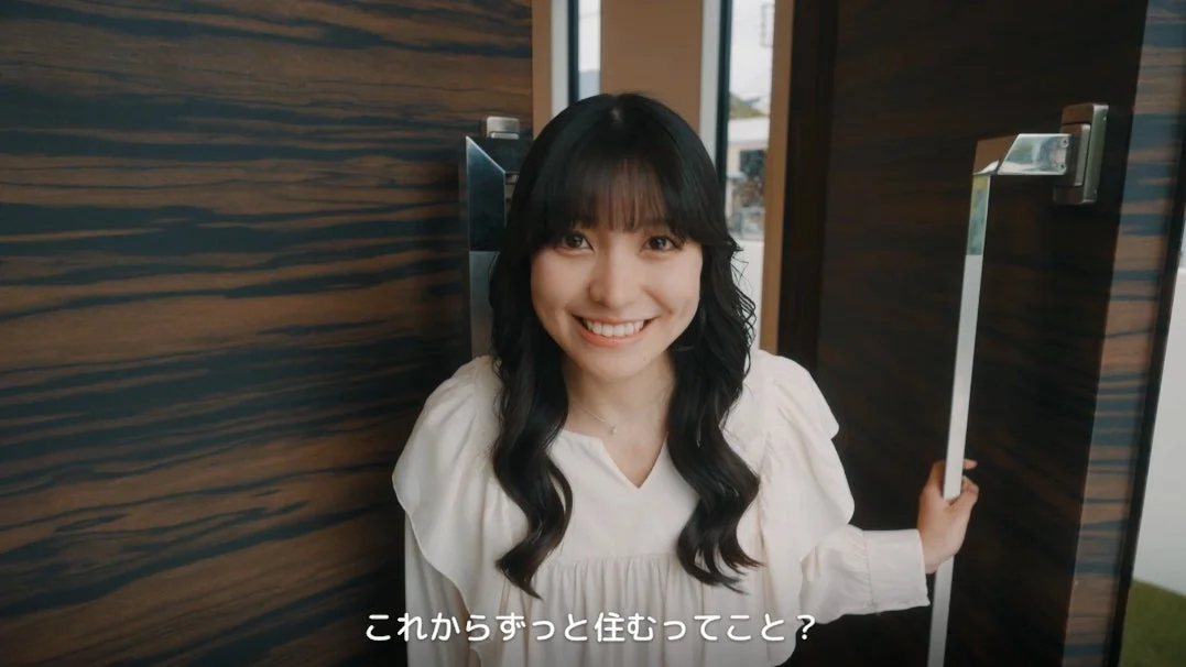 明るく微笑む若い女性が、新しい住居のドアを開けようとしている