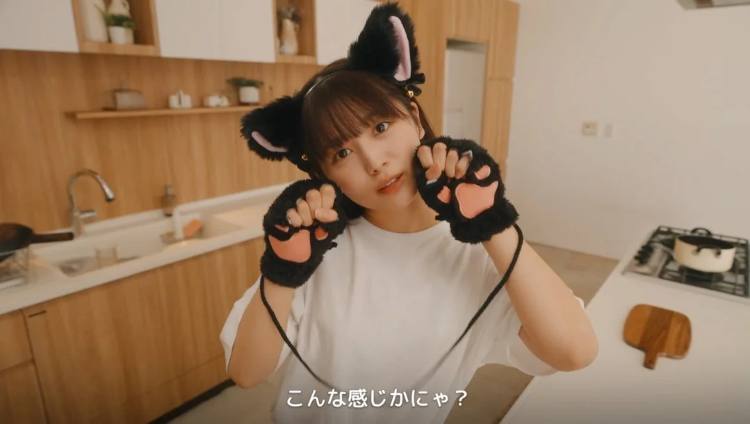 猫耳と猫の手袋を身につけた若い女性が、可愛らしいポーズでカメラを見つめている