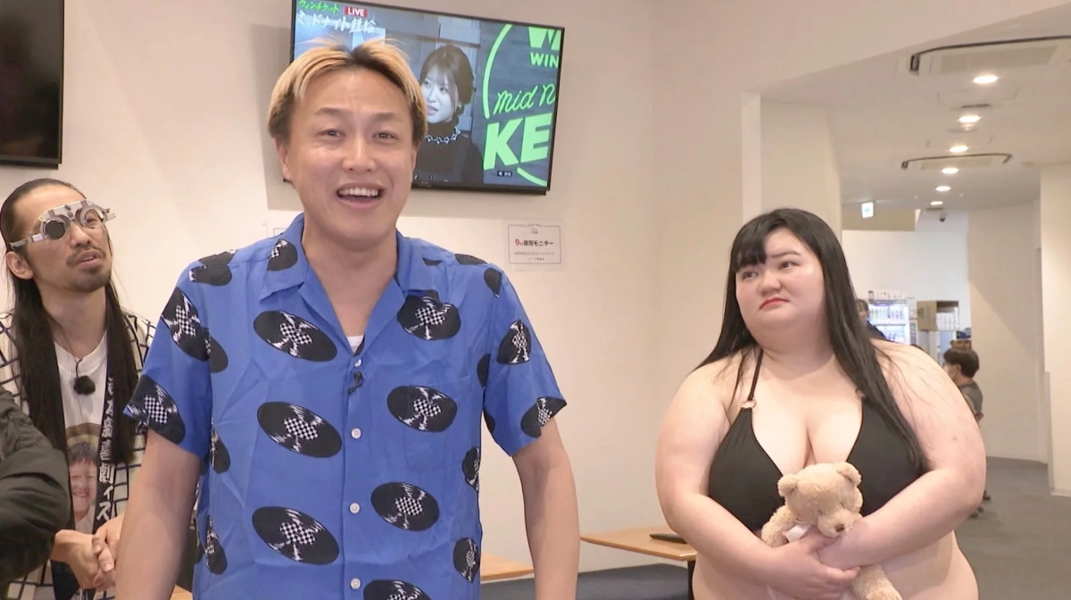 バラエティ番組の一場面、水着の女性と眼鏡の男性