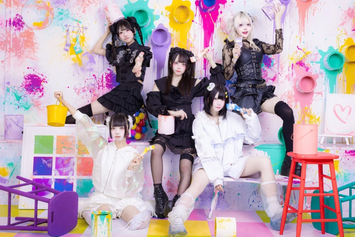 カラフルなペイント空間で楽しげにポーズをとる5人の女性アイドルグループ