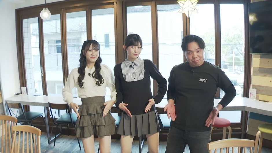 カフェのような屋内でポーズを取るSTU48メンバーと男性