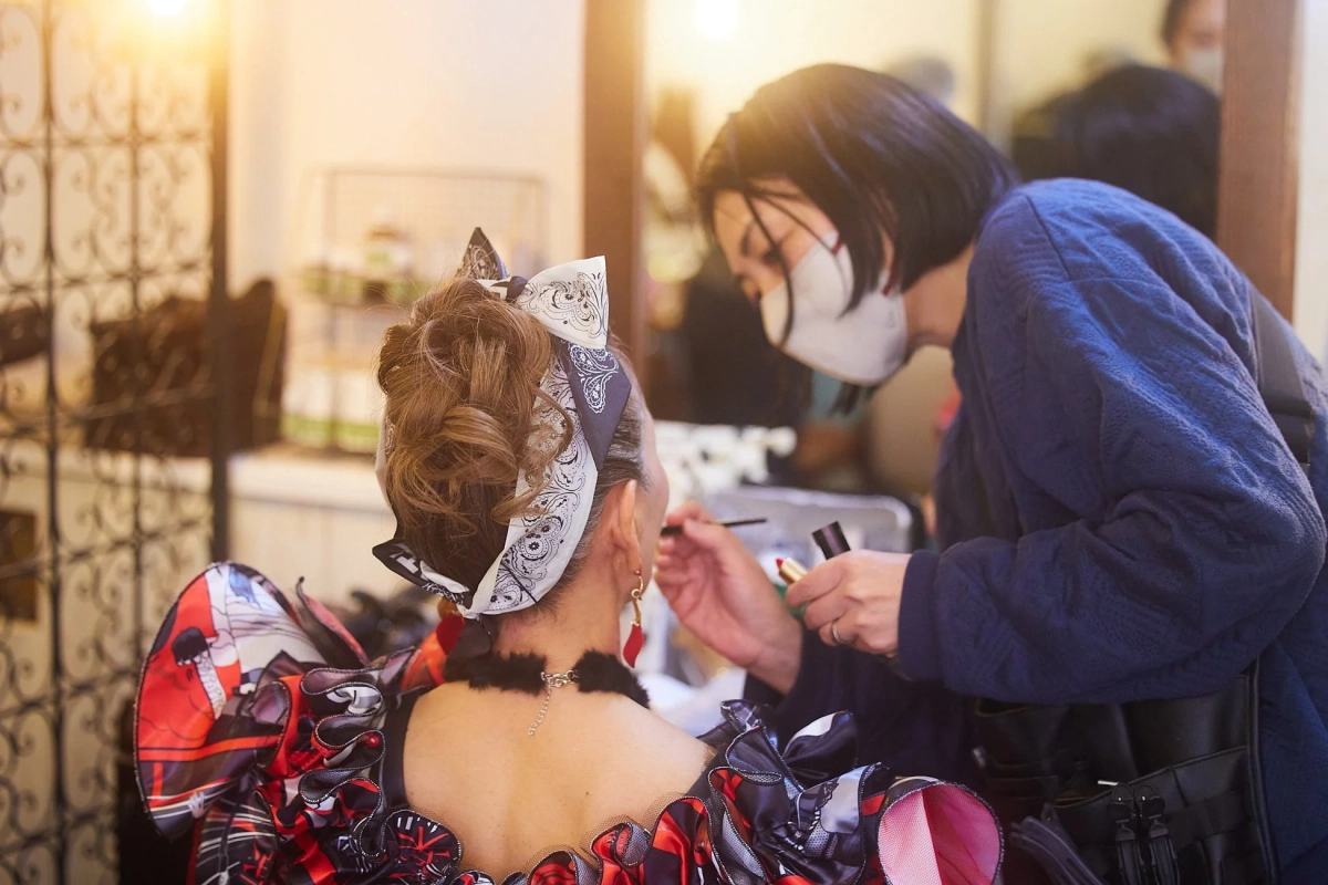 舞台衣装を着た女性がメイクアップアーティストから舞台メイクを施されている場面