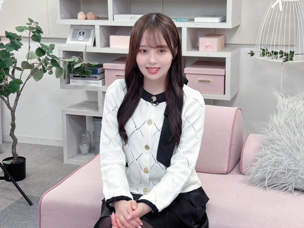 ピンクのソファに座って笑顔を見せる若い女性のポートレート