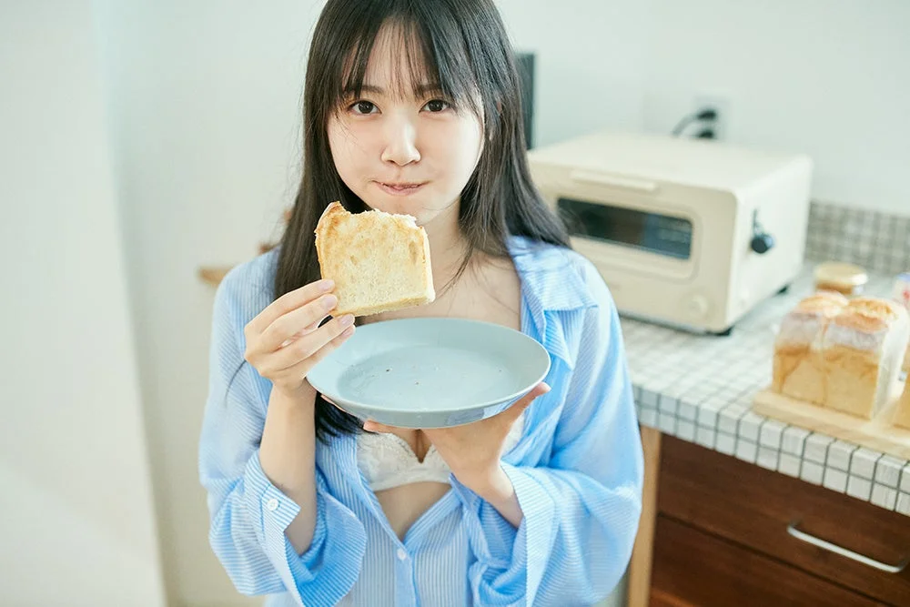 キッチンでトーストを食べる女性