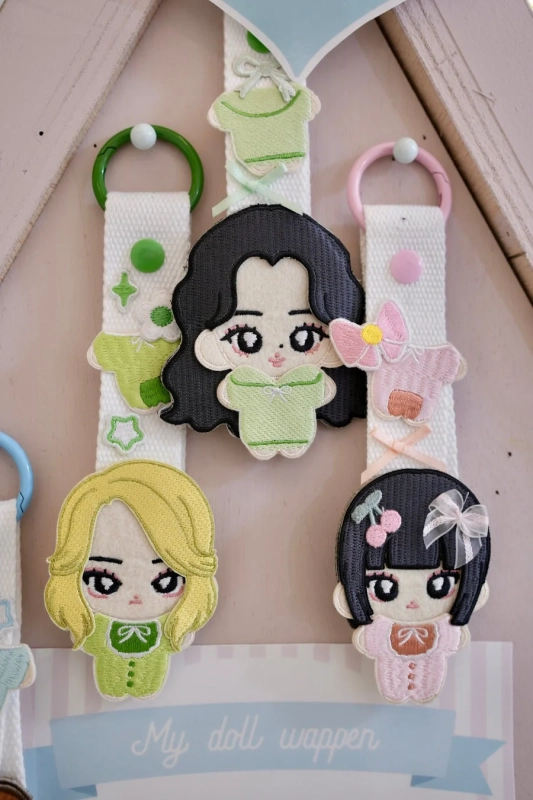 白いストラップに吊るされた、可愛らしい刺繍の人形ワッペンが複数展示されています