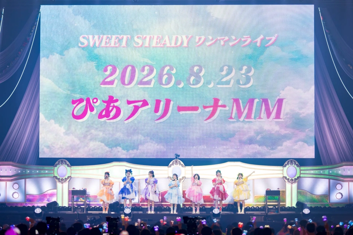 アイドルグループ「SWEET STEADY」のワンマンライブの様子。カラフルな衣装をまとったメンバーがステージでパフォーマンスし、背景のスクリーンには開催日時と会場「2026.8.23 ぴあアリーナMM」が映し出されている。観客がペンライトを振って盛り上がっているライブ会場の風景。