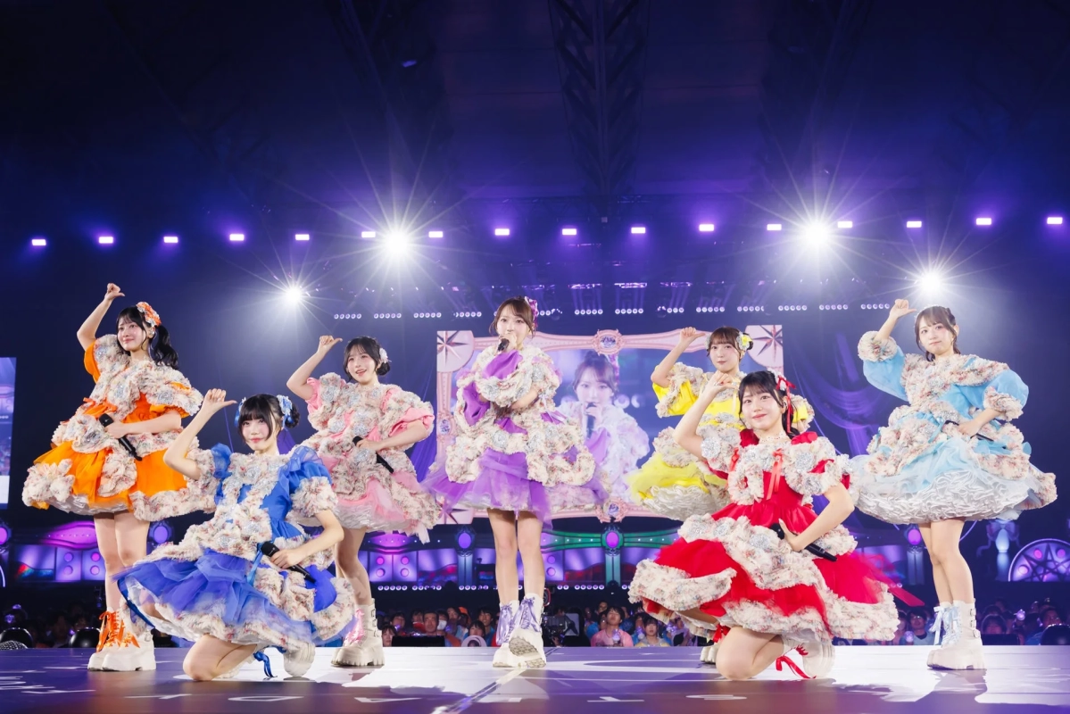 華やかな衣装をまとった複数の女性アイドルグループが、明るいステージで観客を前にパフォーマンスしている様子。笑顔でポーズをとっており、ライブの熱気が伝わる一枚です。