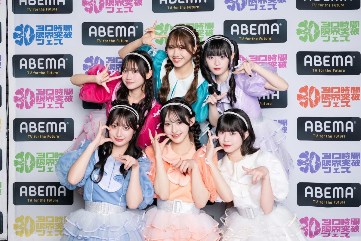 カラフルなフリル衣装を身につけた6人の女性アイドルグループが、ABEMAのロゴと「30時間限界突破フェス」のバナーを背景に、笑顔で可愛らしいポーズを取っています。イベント出演時の集合写真のようです。