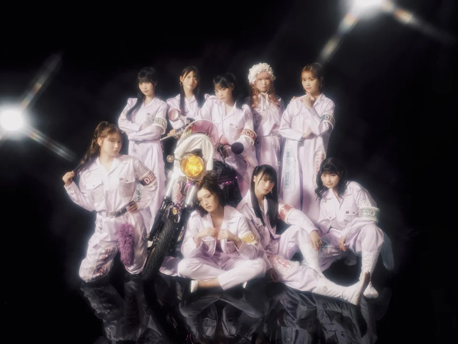 オートバイと紫色の衣装をまとった女性アイドルグループ