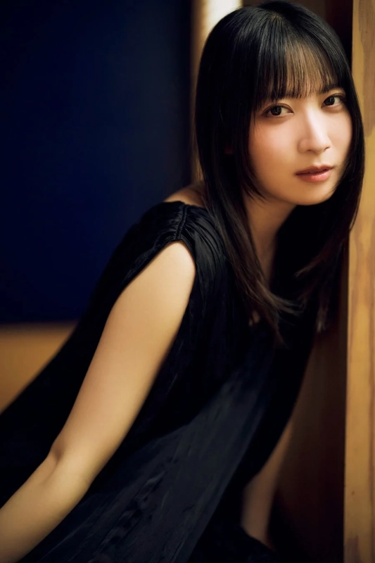 黒い衣装を身につけた若い女性が、落ち着いた表情でカメラを見つめているポートレート写真