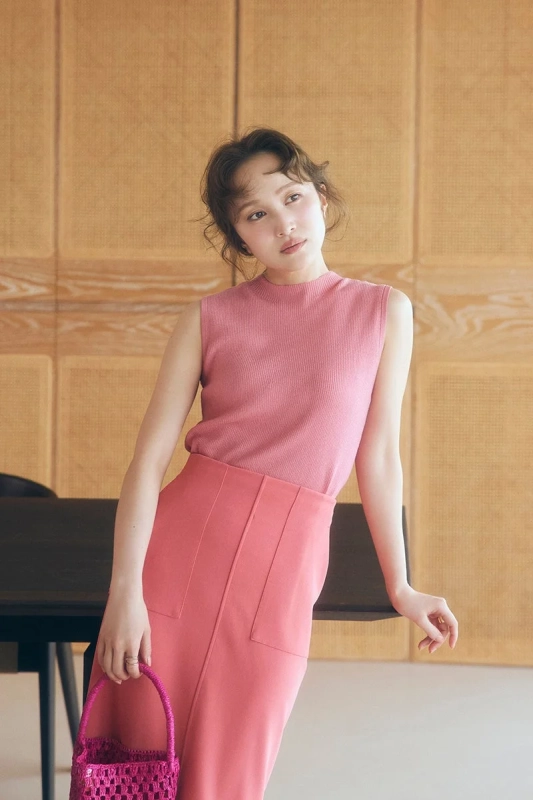 ピンクのノースリーブトップスとスカートを着用し、フューシャピンクのバッグを持った女性のポートレート