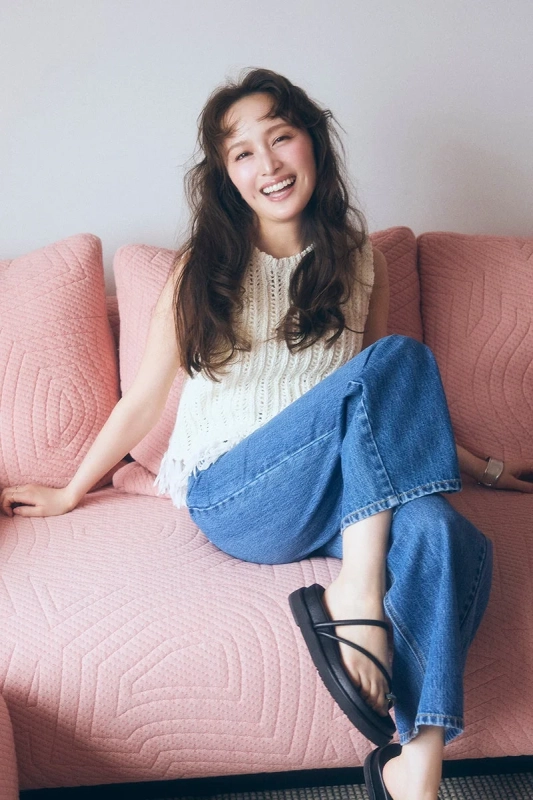 ピンクのソファに座って笑顔を見せる若い女性のポートレート