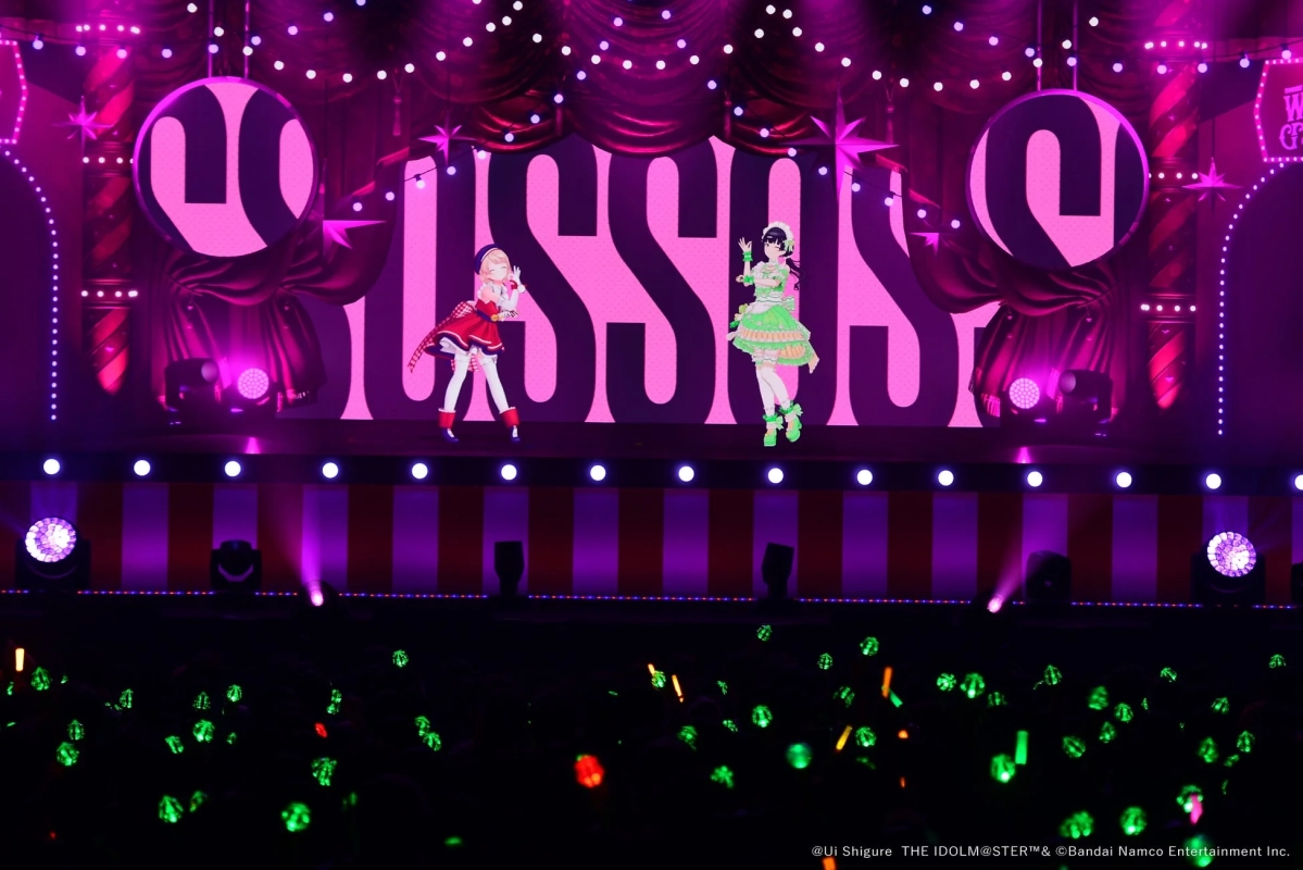バーチャルアイドル二人がピンクの「USSS」の背景が特徴的なステージでパフォーマンスしています。