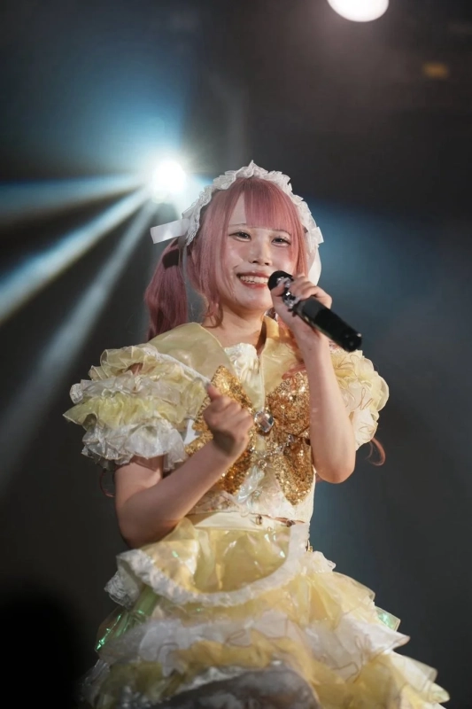 ピンク色の髪の女性アイドルがステージで歌唱