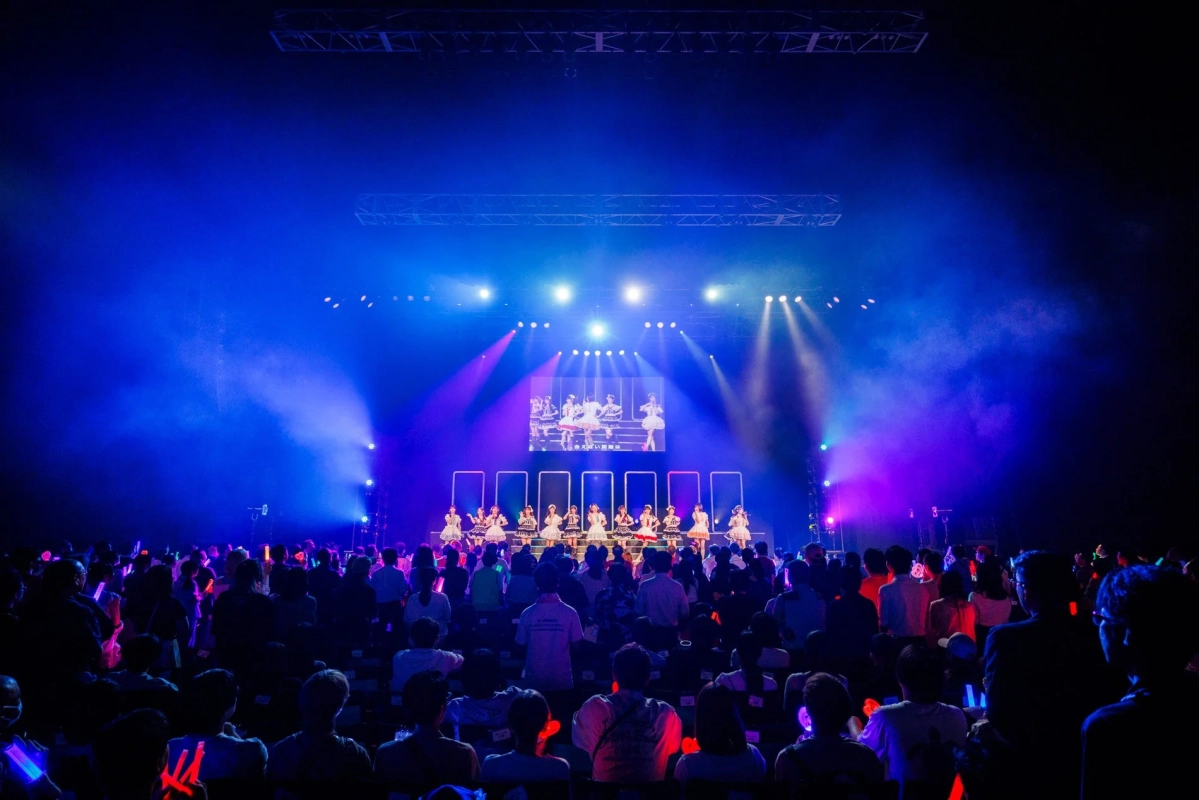 ステージでパフォーマンスするアイドルと観客のペンライト