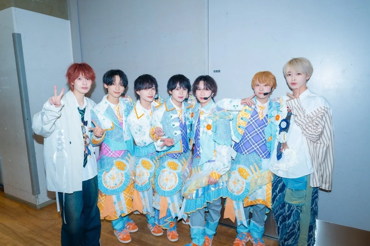 カラフルなステージ衣装をまとった7人のアイドルグループ