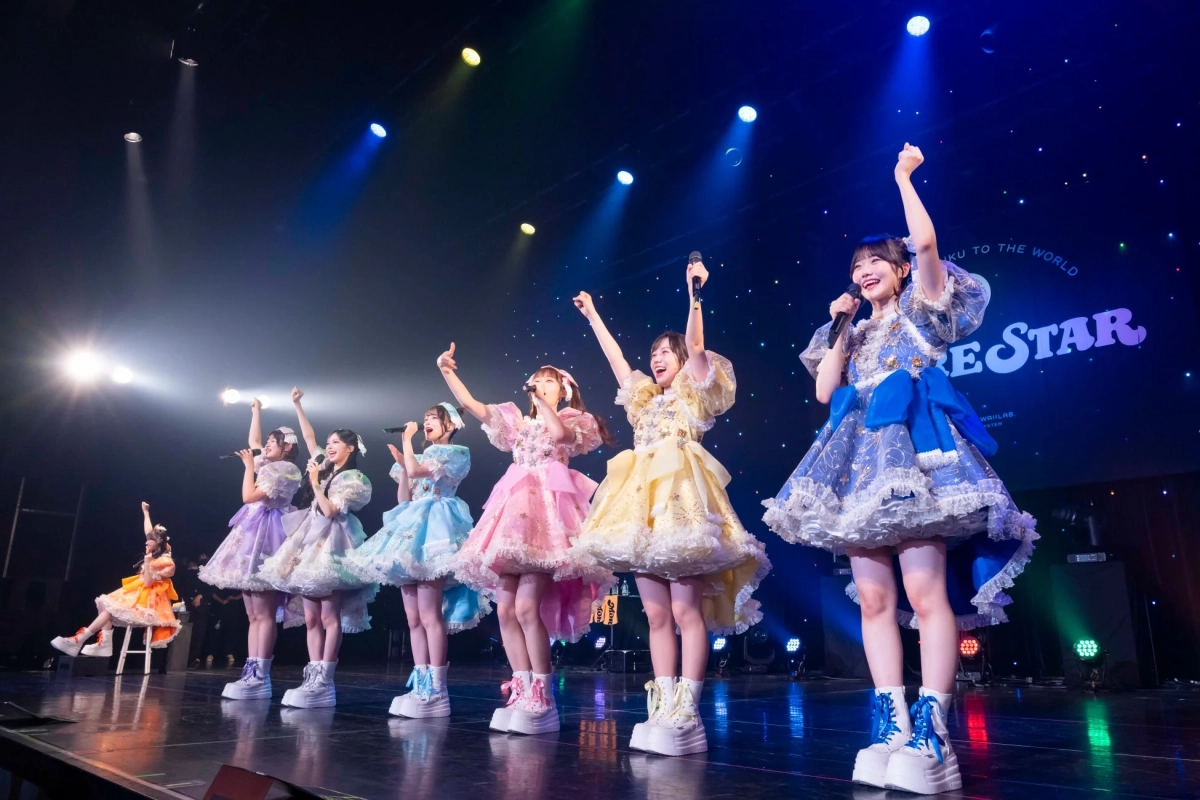 ステージで笑顔でパフォーマンスするアイドルグループ