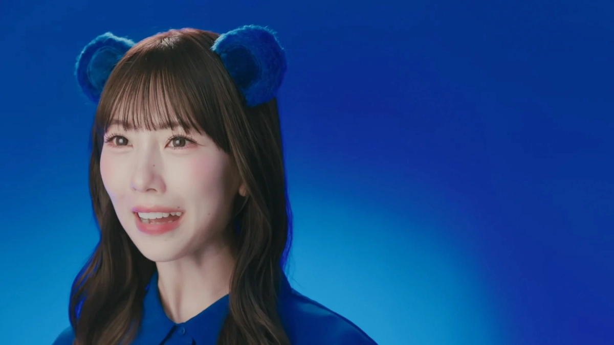 青い耳飾りと青いシャツを着用した熊崎晴香さんのポートレート