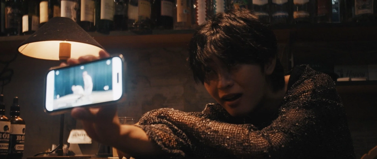 バーのような場所でスマートフォンを見せる男性