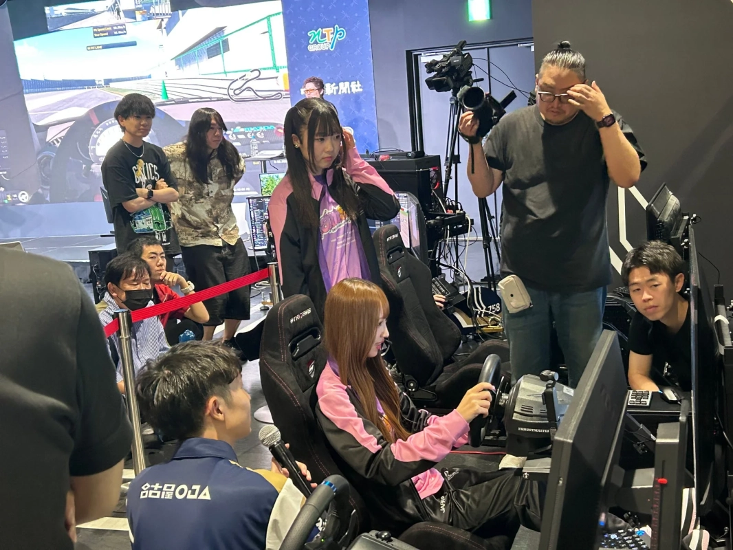イベント会場で、女性が本格的なレーシングシミュレーターを操作している。